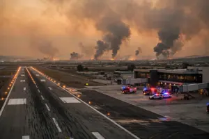 Smoke rises near an airport terminal at dusk as Saudi-Houthi strikes escalate