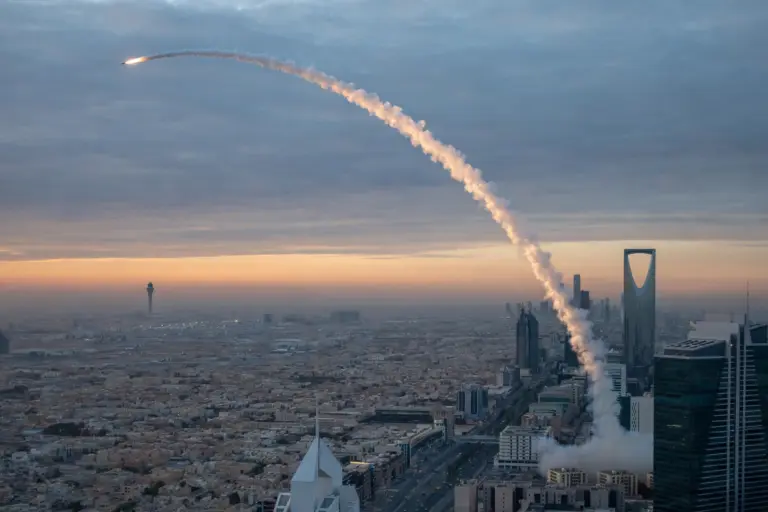 Air defence interceptor missile trail arcing over the Riyadh skyline at dawn