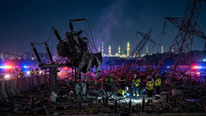 Damaged Taiba power station transformers in Medina at night with emergency crews and the Prophet's Mosque minarets in the distance