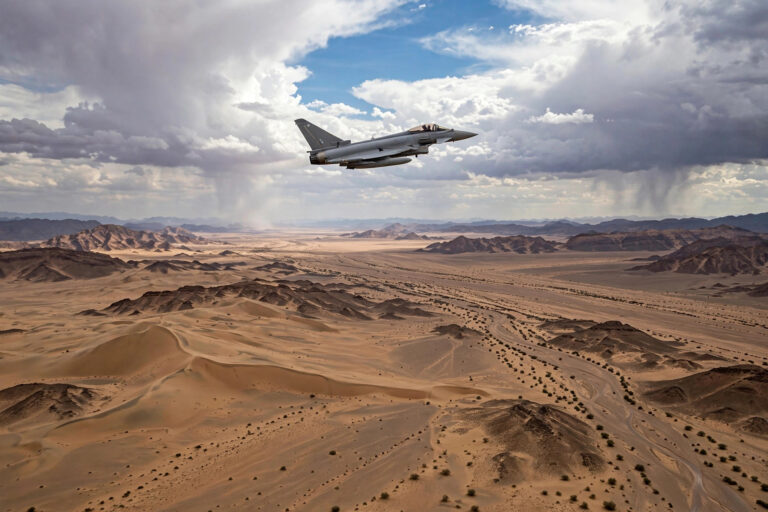 RAF Typhoon fighter jet flying over desert terrain