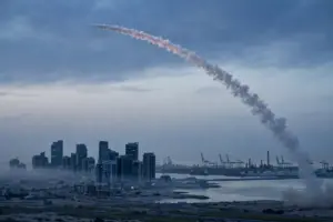 Interceptor missile trail arcing over a Saudi Arabian Eastern Province coastal city skyline at dawn